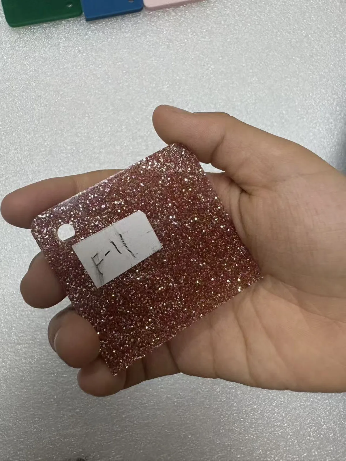 Rose gold glitter acrylic swatch held in hand